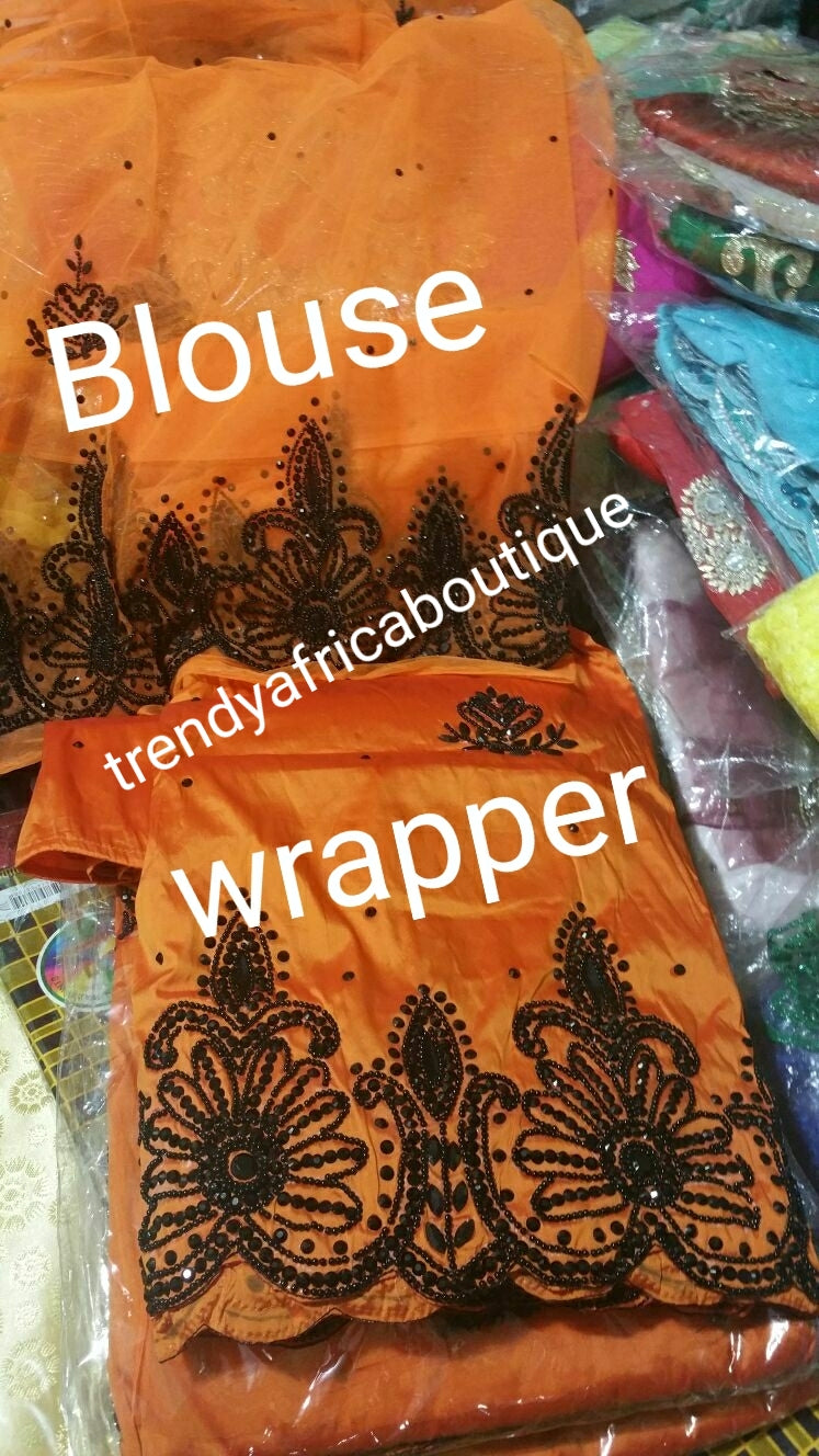 Clearance sale: Exclusive Design of Nigerian Traditional wedding George wrapper in Orange with black beads/stones all over. Quality hand stoned Silk George sold as 5yds with 1.8yds. matching blouse. Price is for the set