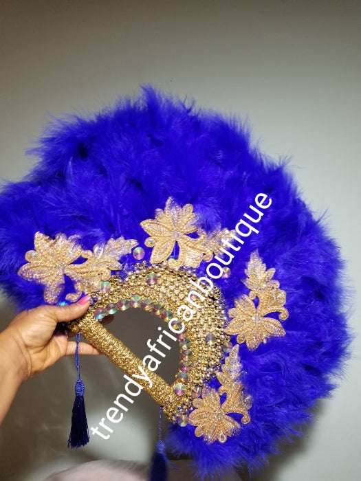 Large Royal blue/gold color, Nigerian made fluffy Feather hand fan. Hand made same front and back design with gold handle, 2 drop tassels and gold petals and beads Bridal-accessories design with beads and flower petal.